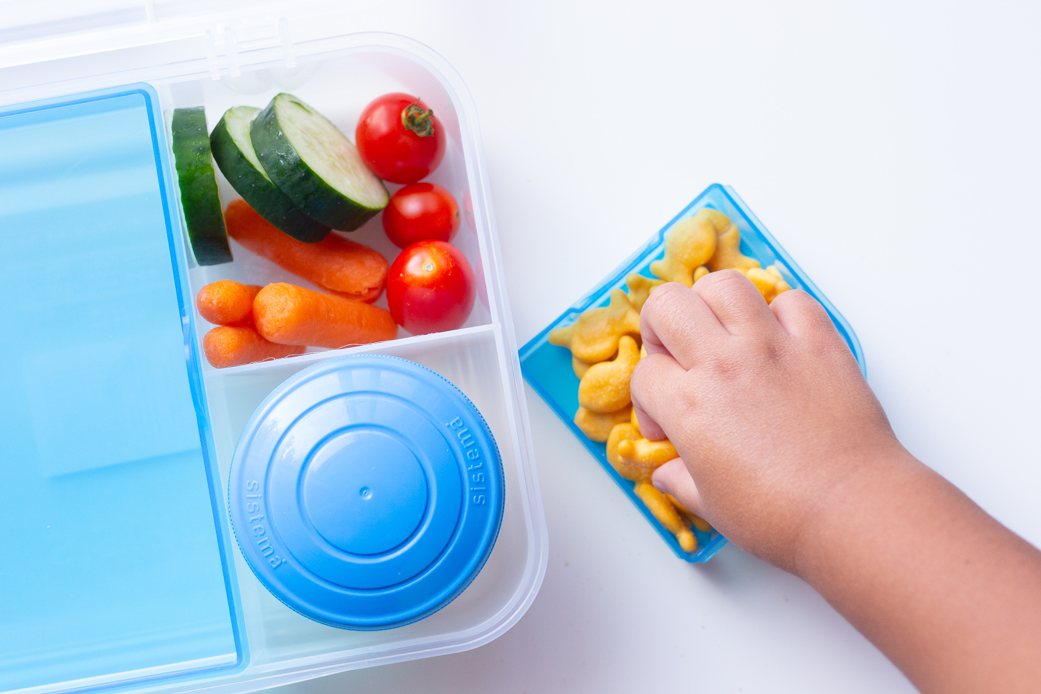 toddler hands grabbing crackers with veggies