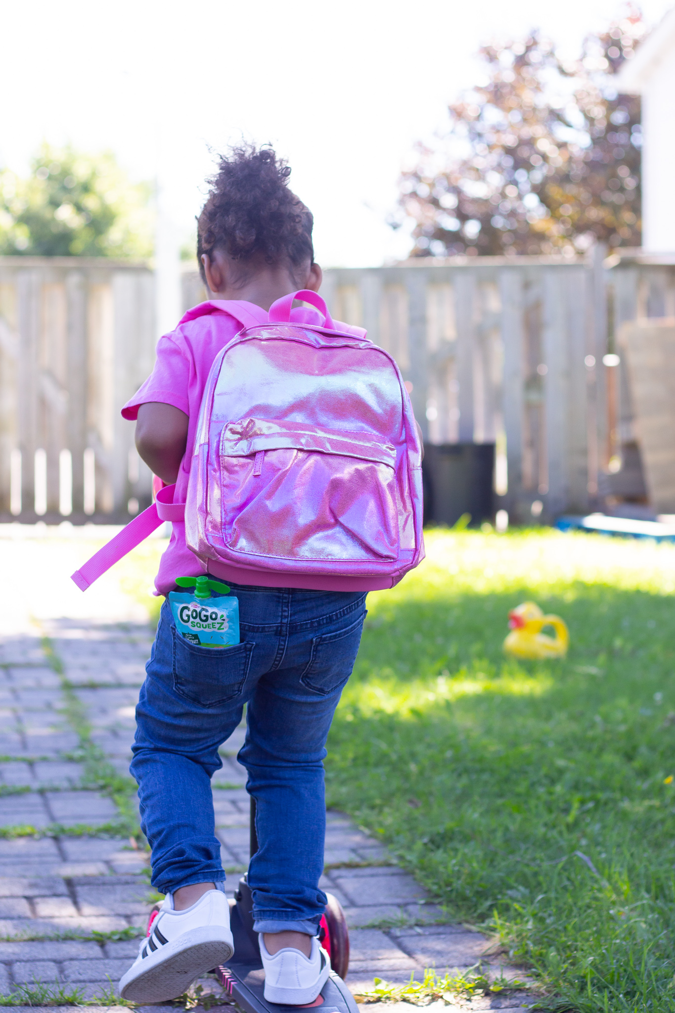 Toddler putting fruit pouch in backpack