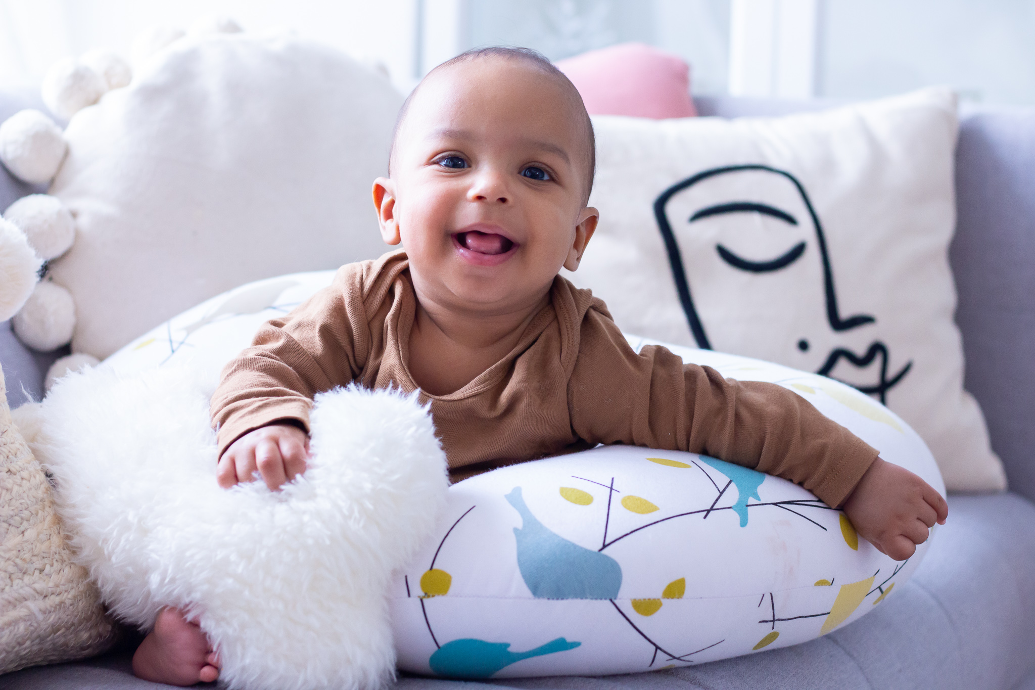 Baby sitting and smiling in nursing pillow